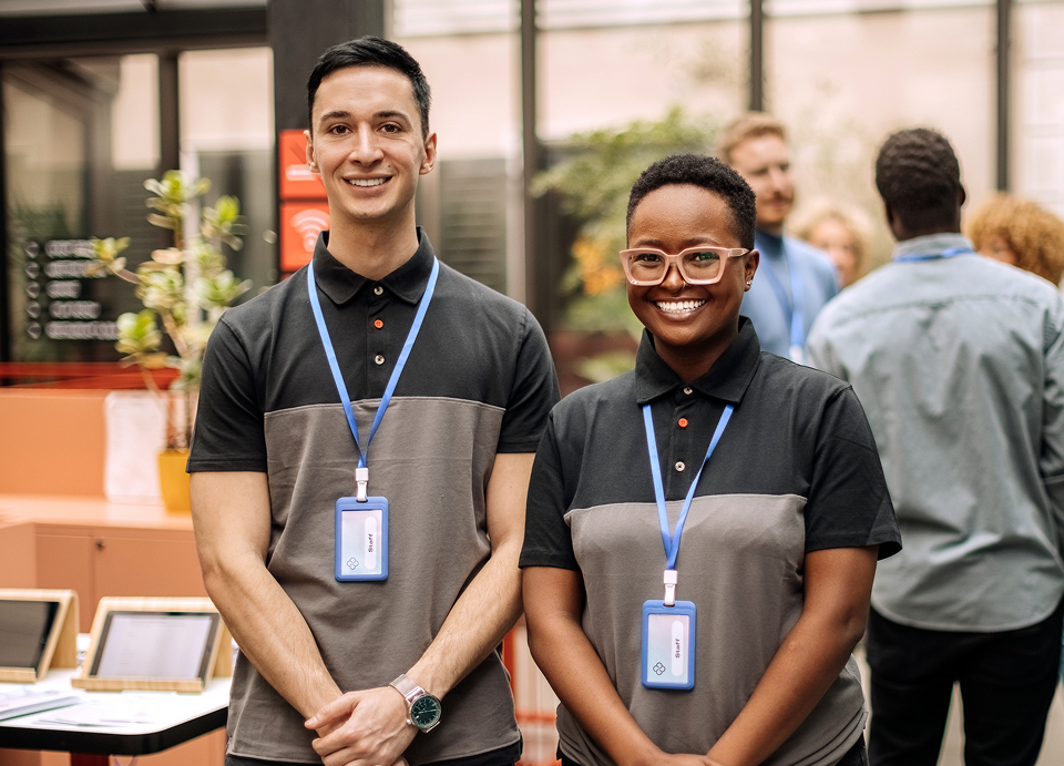 Two smiling employees wearing name badges indoors.